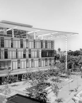 Black and white photo of a modern educational building exterior with trees in the foreground.
